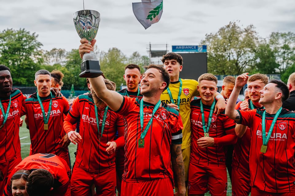 Coventry United players celebrating with a trophy and winners' medals